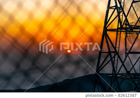 Sunrise burning red through the wire mesh 82612387