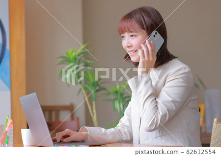Business woman answering the phone with a smile Business woman answering the phone with a smile 82612554