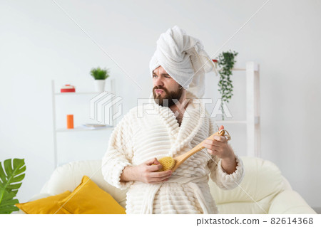 Funny handsome man pretends to play on massage brush as a guitar. Fun, spa and humor concept. 82614368
