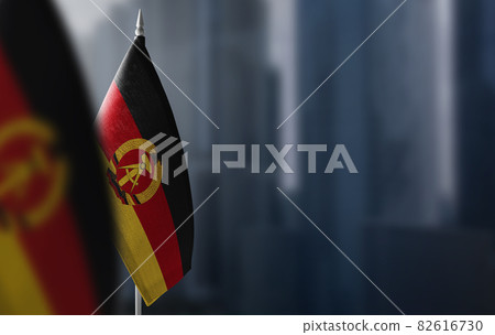 Small flags of GDR on a blurry background of the city 82616730