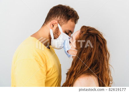 A couple loves and miss eachother and trying to kiss with medical protaction mask. Health care and pandemic. A couple loves and miss eachother and trying to kiss with medical protaction mask. Health care and pandemic. 82619177