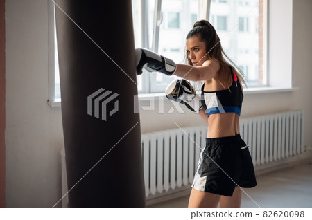 Beautiful woman boxing combat bag with sport trainer together. Girl boxer exercising box punch with personal coach. Beautiful woman boxing combat bag with sport trainer together. Girl boxer exercising box punch with personal coach. 82620098