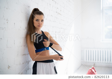 Close up of one young woman wrapping hands with black boxing wraps in gym practice boxing indoor working out fitness female lifestyle 82620113