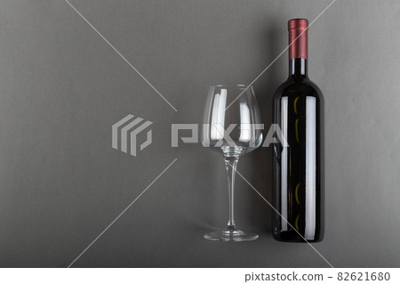 Corked bottle of red wine and empty wine glass on gray background. Alcoholic drink. 82621680