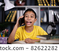 Asian boy holding mobile phone sitting in a chair in the reading room. 82622282