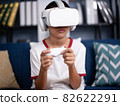 asian boy wearing virtual reality googles at home, remote education experiment, future today, new online education, indoor lifestyle. 82622291