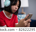 girl wearing headphones using smartphone, interested child listening to favorite music, chatting in social network or playing game online. 82622295