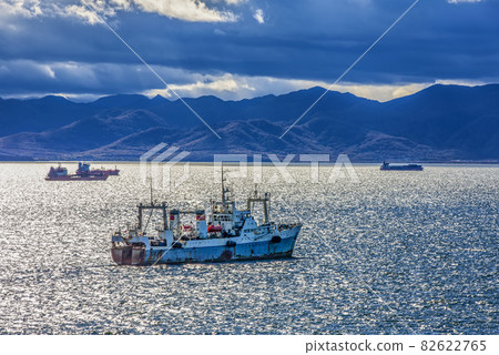 large fishing vessel on the background of hills and volcanoes. Selective focus large fishing vessel on the background of hills and volcanoes. Selective focus 82622765