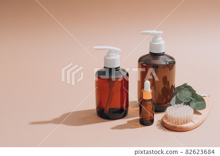 Set of natural bathroom amenities - glass dropper bottles with natural organic cosmetics, natural face or body dry brush, eucalyptus oil, cream, lotion, essential oils on brown background. Mockup Set of natural bathroom amenities - glass dropper bottles with natural organic cosmetics, natural face or body dry brush, eucalyptus oil, cream, lotion, essential oils on brown background. Mockup 82623684
