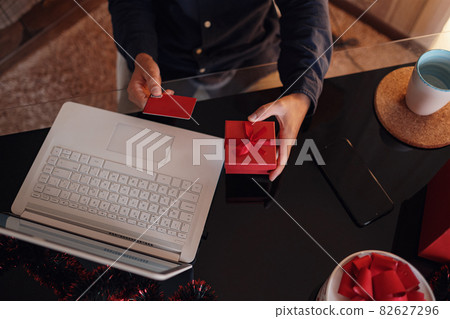 Happy man wearing Santa Claus hat holding gift or credit card Happy man wearing Santa Claus hat holding gift or credit card 82627296