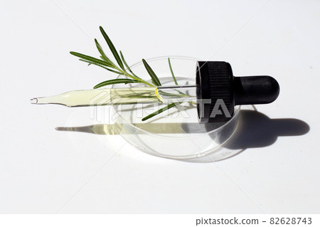 Essential oil with rosemary leaves in petri dishes on white background. 82628743
