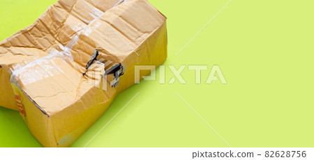 Damaged cardboard box with hole on green background. Damaged cardboard box with hole on green background. 82628756