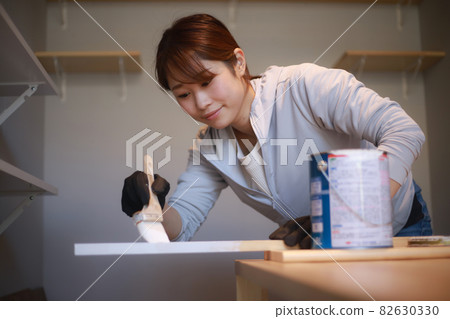 A woman painting lumber with a brush A woman painting lumber with a brush 82630330