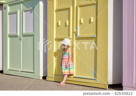 Girl in a colored dress near colorful wooden houses on the ocean Saint aubin sur mer 82630822