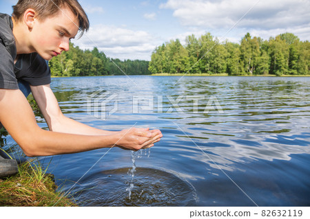 Boy scoops up raw water from a lake 82632119