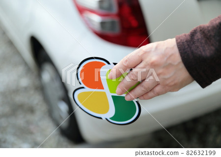 Senior woman's hand putting an elderly mark on a car Senior woman's hand putting an elderly mark on a car 82632199