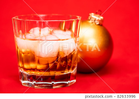 Glass of whiskey with christmas bauble on red background christmas drink concept 82633996