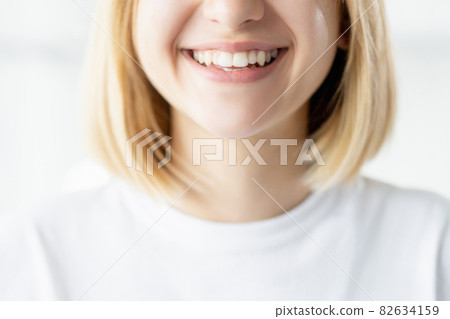 Healthy smile. Dental care. Stomatology treatment. Unrecognizable woman face closeup with perfect white teeth isolated on light background. 82634159