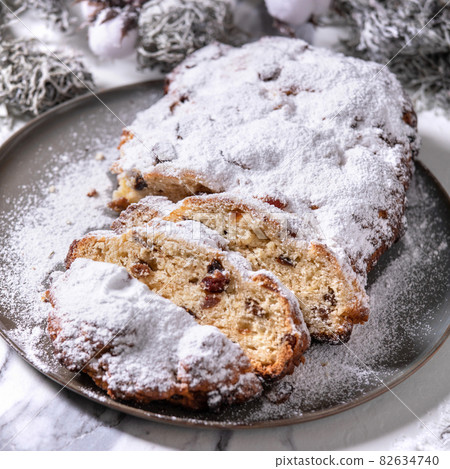Christmas baking stollen cake with xmas decorations over white marble Christmas baking stollen cake with xmas decorations over white marble 82634740