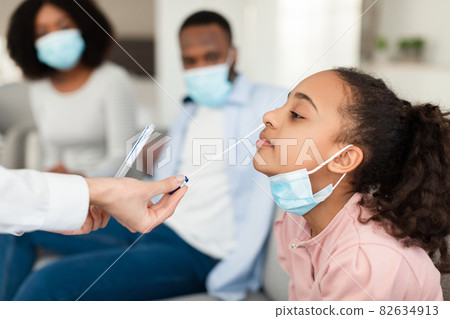 Nurse taking nasal PCR test sample from black teen girl 82634913