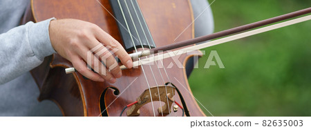 Photography of a street musician plays the cello on a city street on a spring day. Frontal view. Festive mood. Street concert. Closeup photography	 82635003