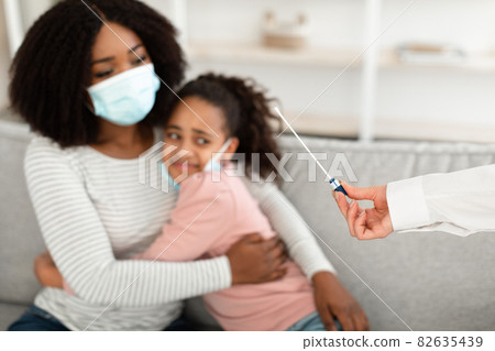 Doctor taking PCR test sample from afraid black teen girl Doctor taking PCR test sample from afraid black teen girl 82635439