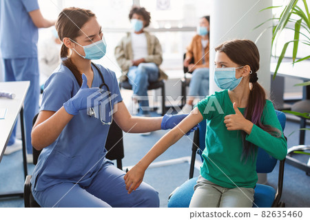 Vaccinated Girl And Nurse Gesturing Thumbs Up At Clinic Vaccinated Girl And Nurse Gesturing Thumbs Up At Clinic 82635460