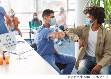 Black Guy In Medical Mask Bumping Elbows With Young Male Doctor 82635593