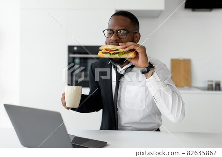 Black man rushing to work eating sandwich at home Black man rushing to work eating sandwich at home 82635862