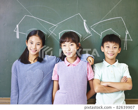 asian elementary schoolchildren standing underneath chalk-drawn doctoral hats in front of blackboard 82639907