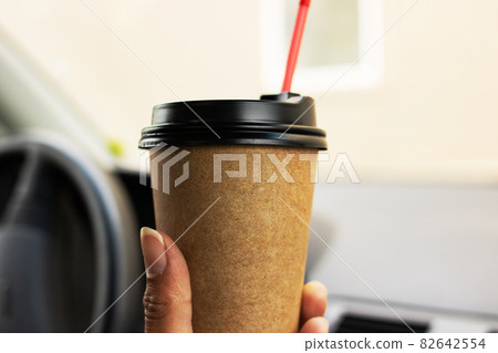 Paper cup of coffee in hand in car 82642554