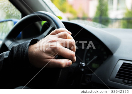 Hand on the steering wheel of a car 82642555