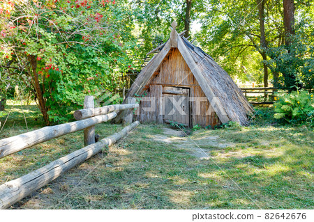 An old cellar covered with reeds and a thatched roof in the summer garden of a country estate. 82642676