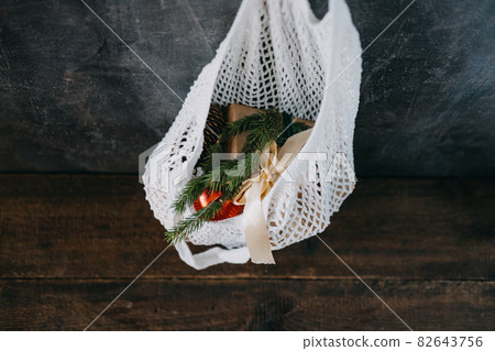 Zero waste, Sustainable, green, eco-friendly Christmas. Eco friendly mesh net shopping bag with craft gift boxes and green fir tree branch. Mesh Reusable Cotton Grocery Bag with Christmas gifts Zero waste, Sustainable, green, eco-friendly Christmas. Eco friendly mesh net shopping bag with craft gift boxes and green fir tree branch. Mesh Reusable Cotton Grocery Bag with Christmas gifts 82643756