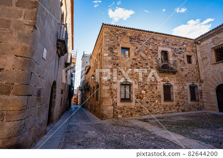 Narrow alley with old stone buildings at Caceres, Extremadura, Spain. 82644200
