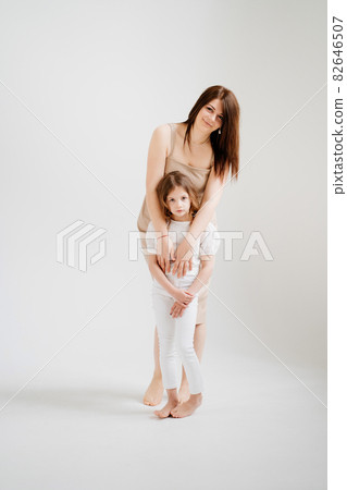 Mom and daughter pose in a white photo studio. 82646507