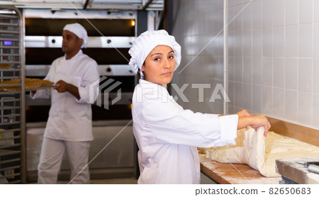 Woman baker kneading dough for baking bread 82650683