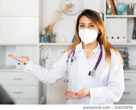 Female doctor in medical mask inviting to doctor's office Female doctor in medical mask inviting to doctor's office 82650956