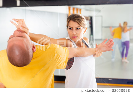 Strong cheerful woman is training with man on the self-defense course 82650958