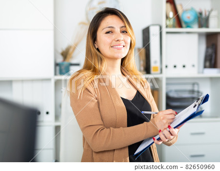 Young colombian woman manager holding clipboard Young colombian woman manager holding clipboard 82650960