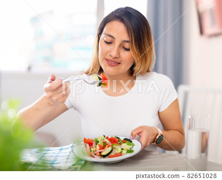 Colombian housewife eating vegetable salad at table at home Colombian housewife eating vegetable salad at table at home 82651028