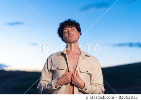 Portrait during dusk of a non binary male posing relaxed Portrait during dusk of a non binary male posing relaxed 82652810