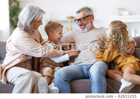Playful kids and grandmother tickling grandpa while spending time together on weekend Playful kids and grandmother tickling grandpa while spending time together on weekend 82655295