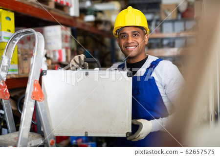 Smiling latin american foreman standing with tool case in store Smiling latin american foreman standing with tool case in store 82657575