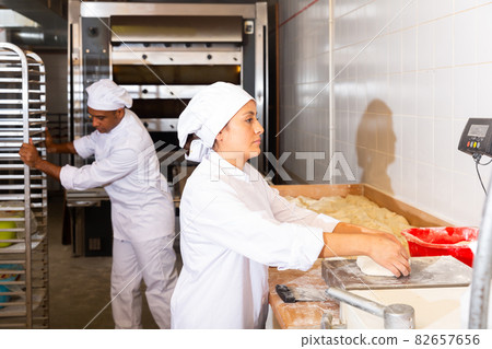 Baker weighs dough on scales in bakery 82657656