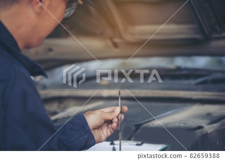 Car Mechanic man hand checking dipstick engine oil car mechanical on site service. Close up hand man check engine oil level Locate dipstick, wipe clean, check dipstick level before fill up engine oil Car Mechanic man hand checking dipstick engine oil car mechanical on site service. Close up hand man check engine oil level Locate dipstick, wipe clean, check dipstick level before fill up engine oil 82659388
