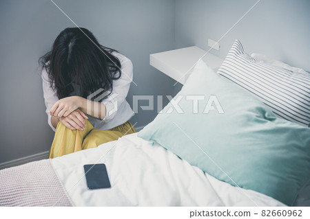 A woman holding her head beside the bed A woman holding her head Depressed woman A woman holding her head beside the bed A woman holding her head Depressed woman 82660962