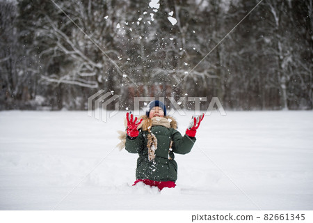 Happy child girl plaing with snow on a snowy winter walk 82661345