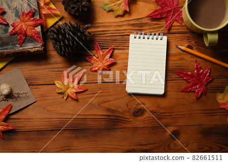 Empty notepad, coffee cup, pine cone and maple leaves on wooden table. 82661511