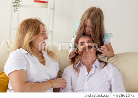 Family sitting on sofa in their living room. Daughter have injury hand but she is happy be together her family. 82661572